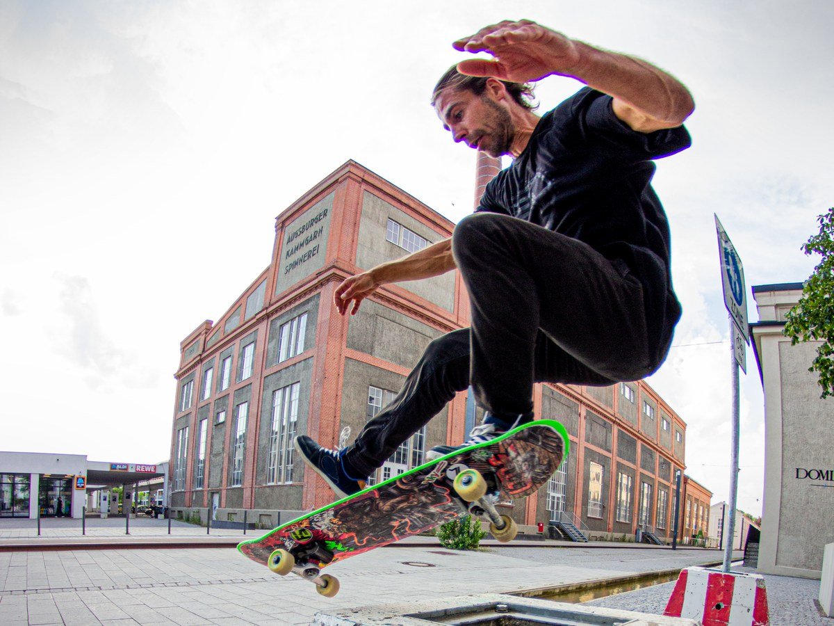 Skater popping a high ollie over a red and white striped concrete barrier